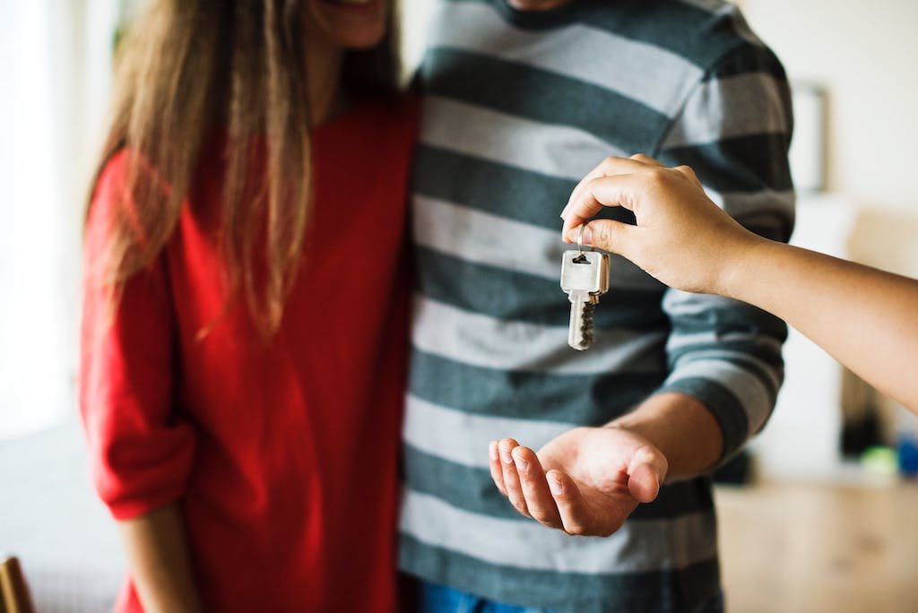a couple, from shoulders down, getting keys to home